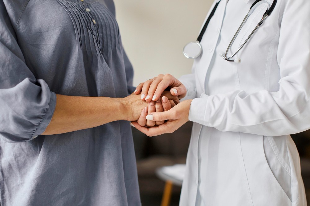 One person gently holding another person's hands.