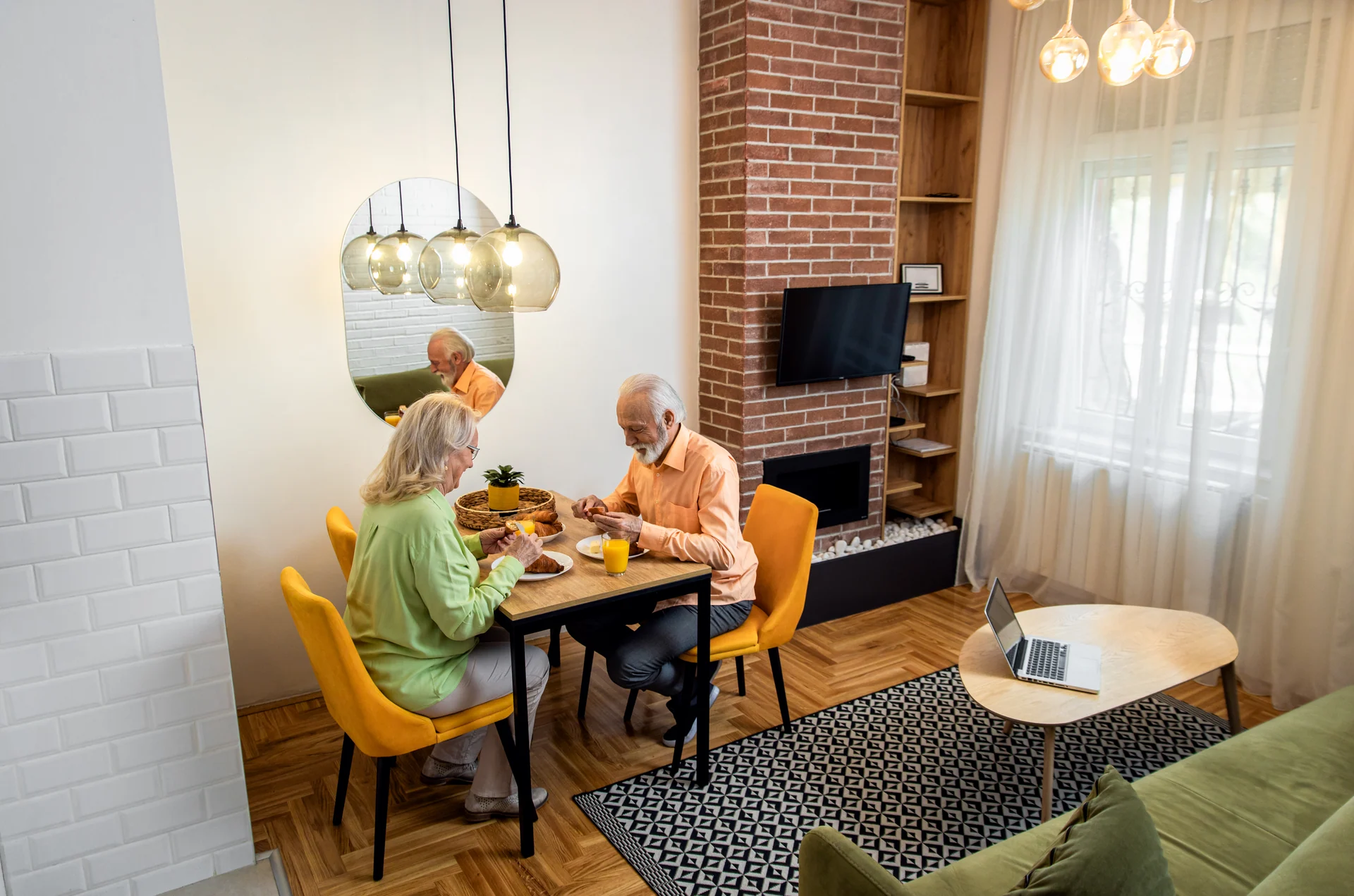 An older couple sharing breakfast at a table in a bright room.